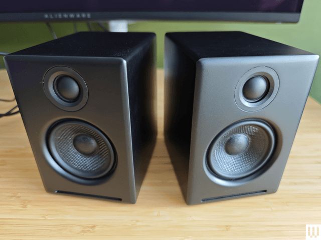 Audio Engine A2 Plus, two small black speakers on top of a wooden desk